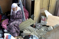 A Palestinian women sits in the rubble of her home destroyed by IDF soldiers during an arrest raid in the West Bank village of Beit Rima, October 25, 2001
