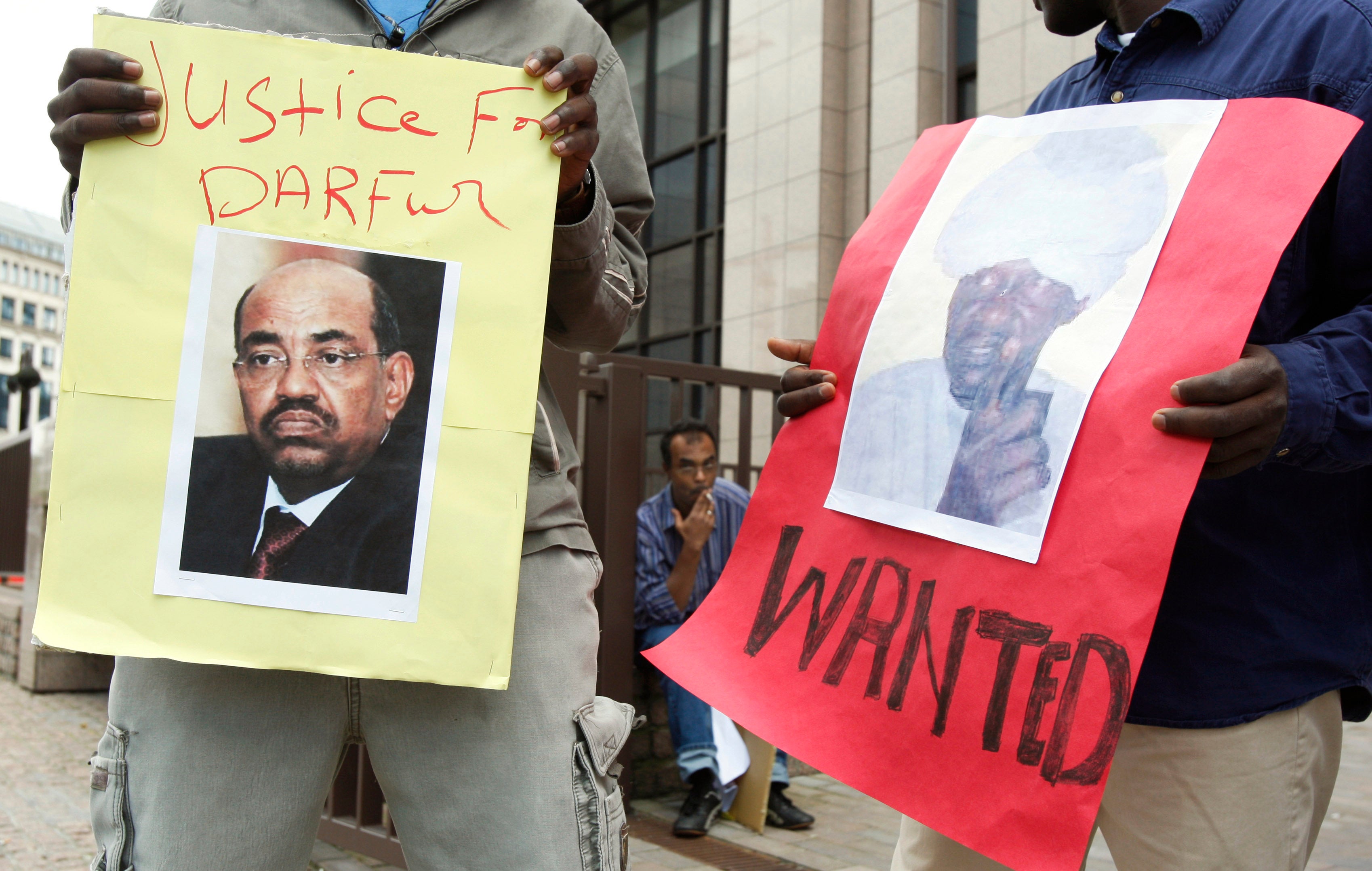 Protesters hold posters of Sudan's then-President Omar Hassan al-Bashir and Janjaweed leader Ali Kosheib (R) outside the European Union Council in Brussels, July 2008.