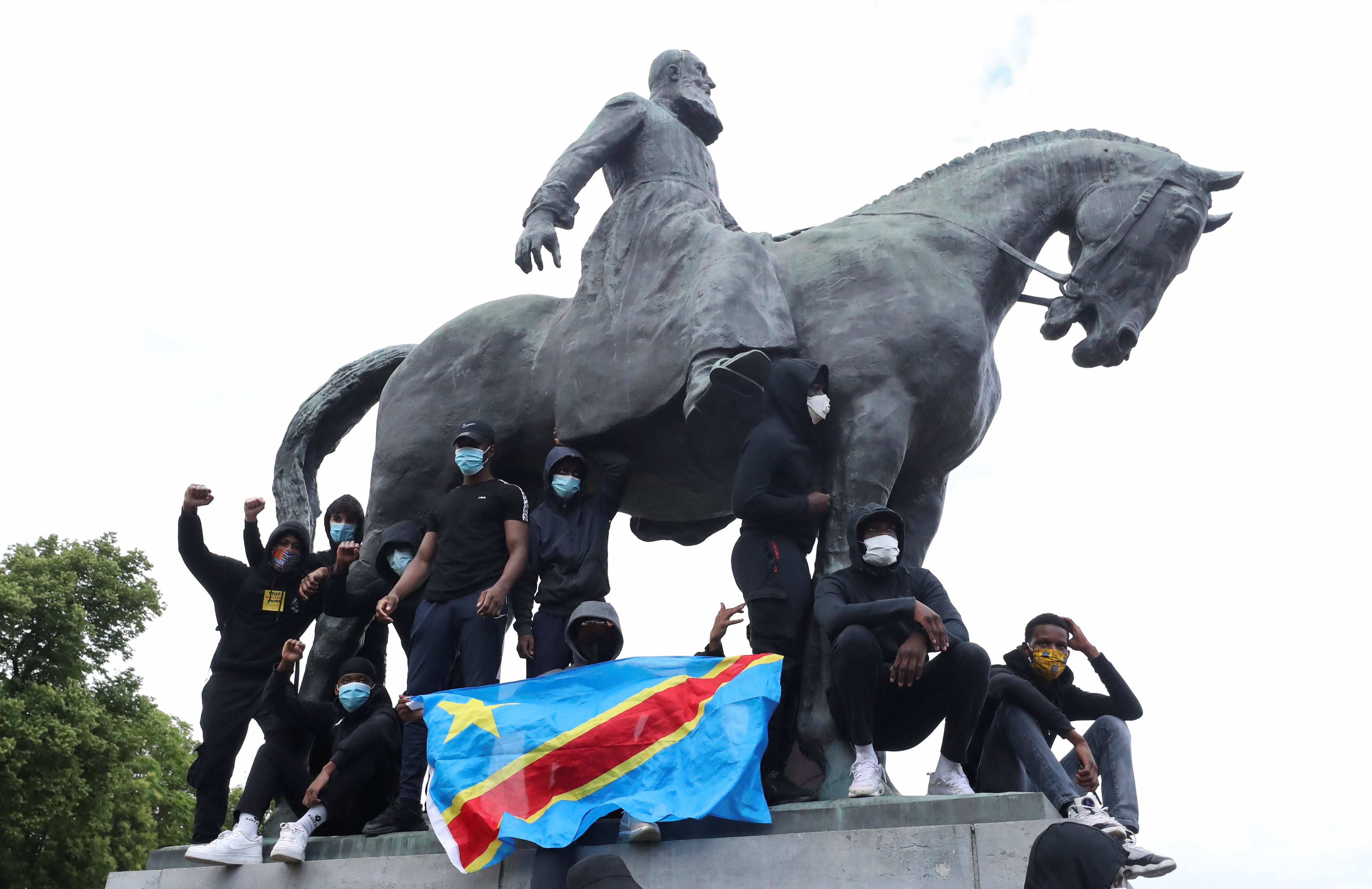 Demonstrators stand on the statue of Leopold II as one of them holds a national flag of the Democratic Republic of Congo during a protest for the end of racial injustice in Brussels, Belgium, June 7, 2020.