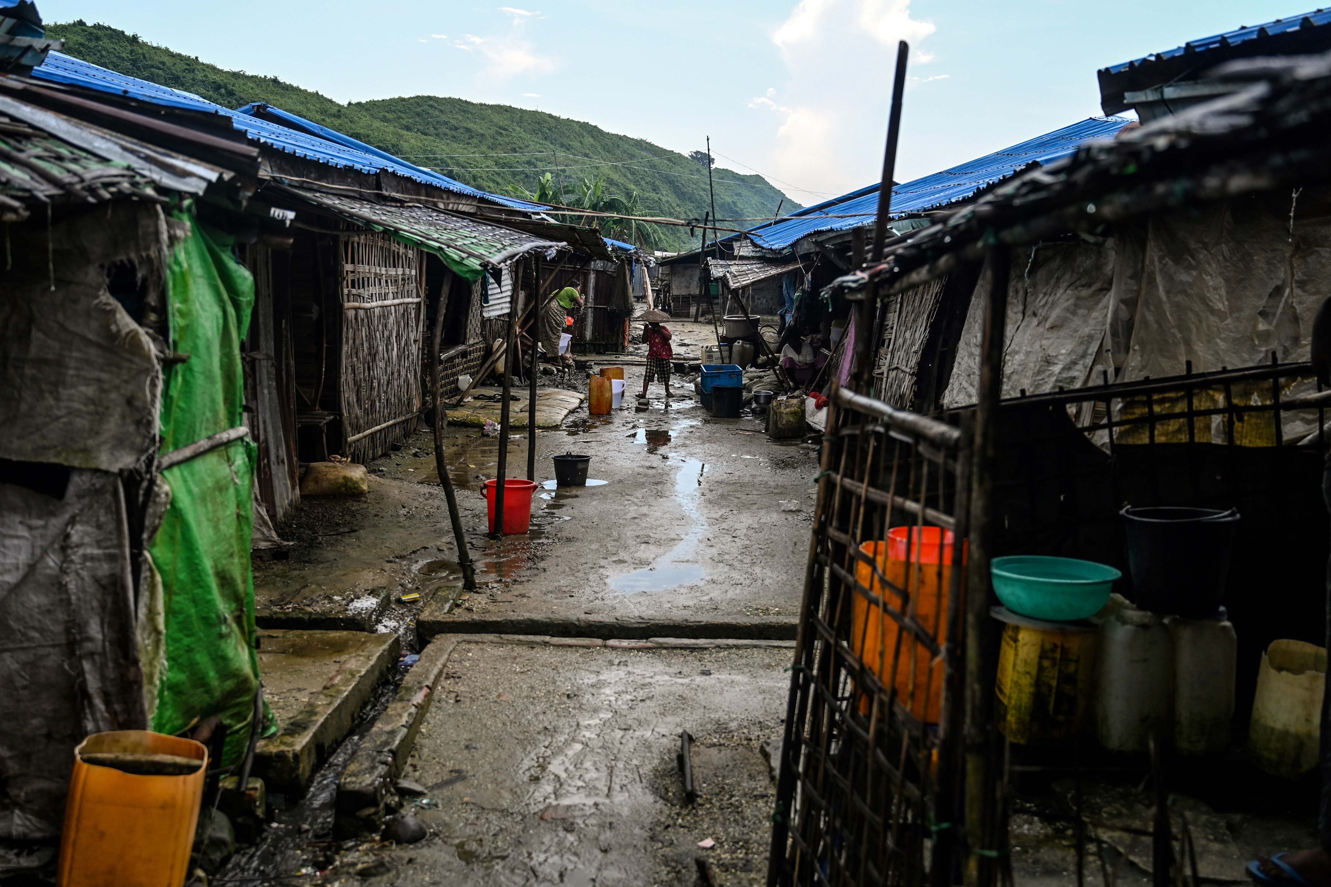 A boy walks down a muddy path in between makeshift buildings