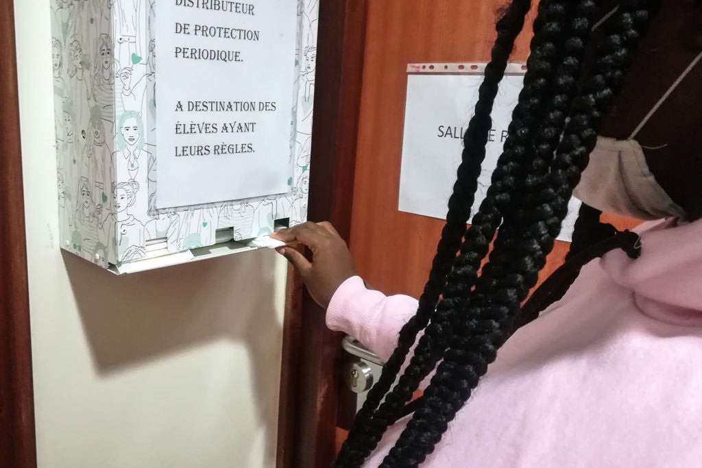 A pupil removes a free organic sanitary napkin from a dispenser at a high school
