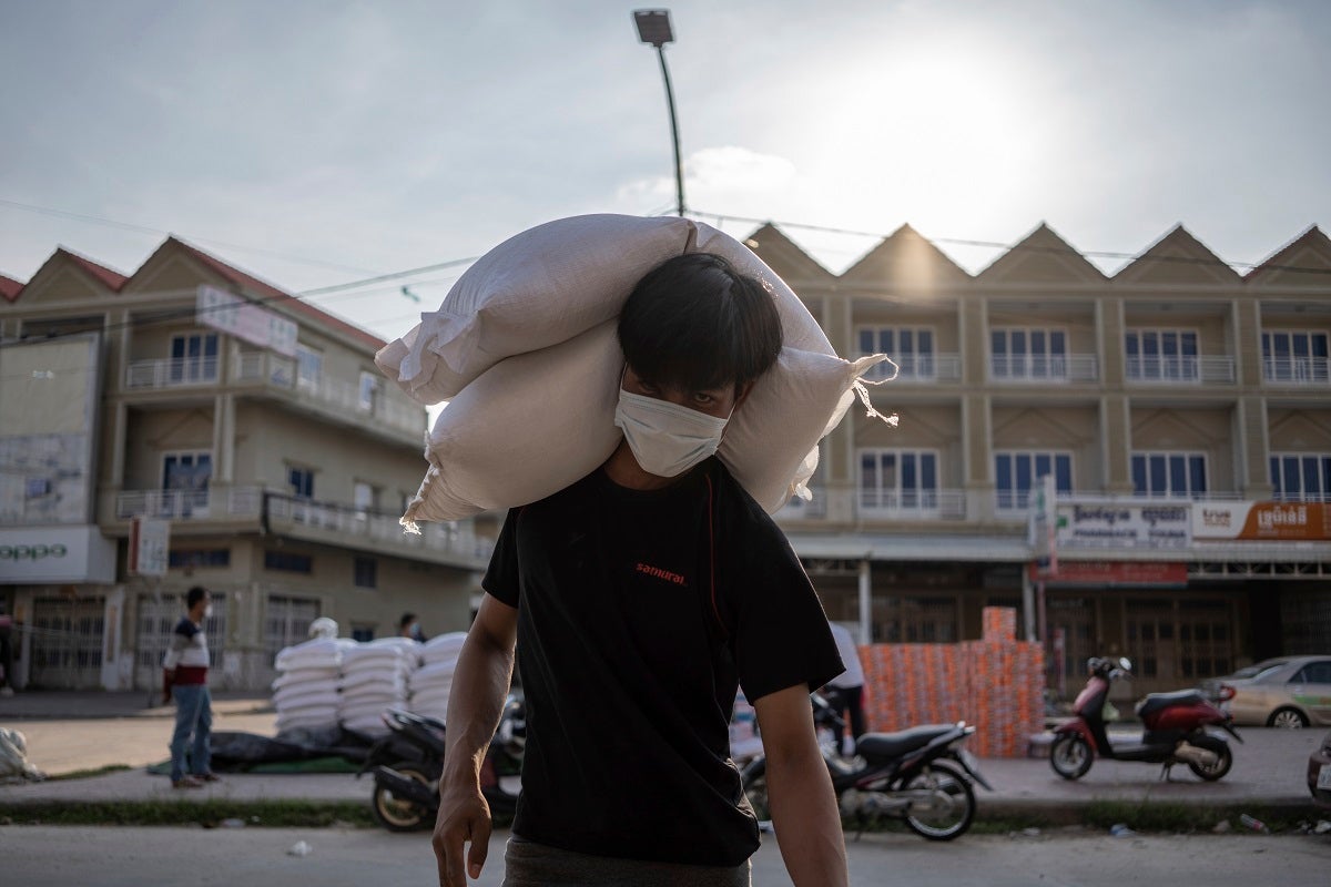 A resident of a Red Zone carries bags of rice donated to his house during the coronavirus pandemic.