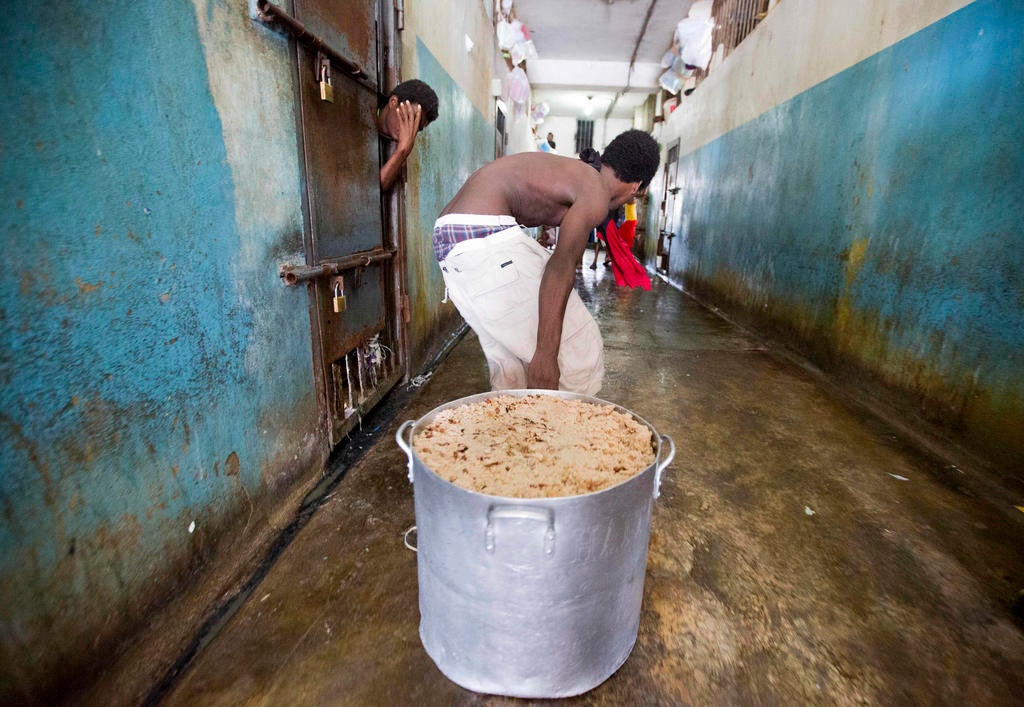 A detainee pulls a large stock pot filled with rice and beans during lunch inside the National Penitentiary in downtown Port-au-Prince, Haiti, on Febuary. 13, 2017. 