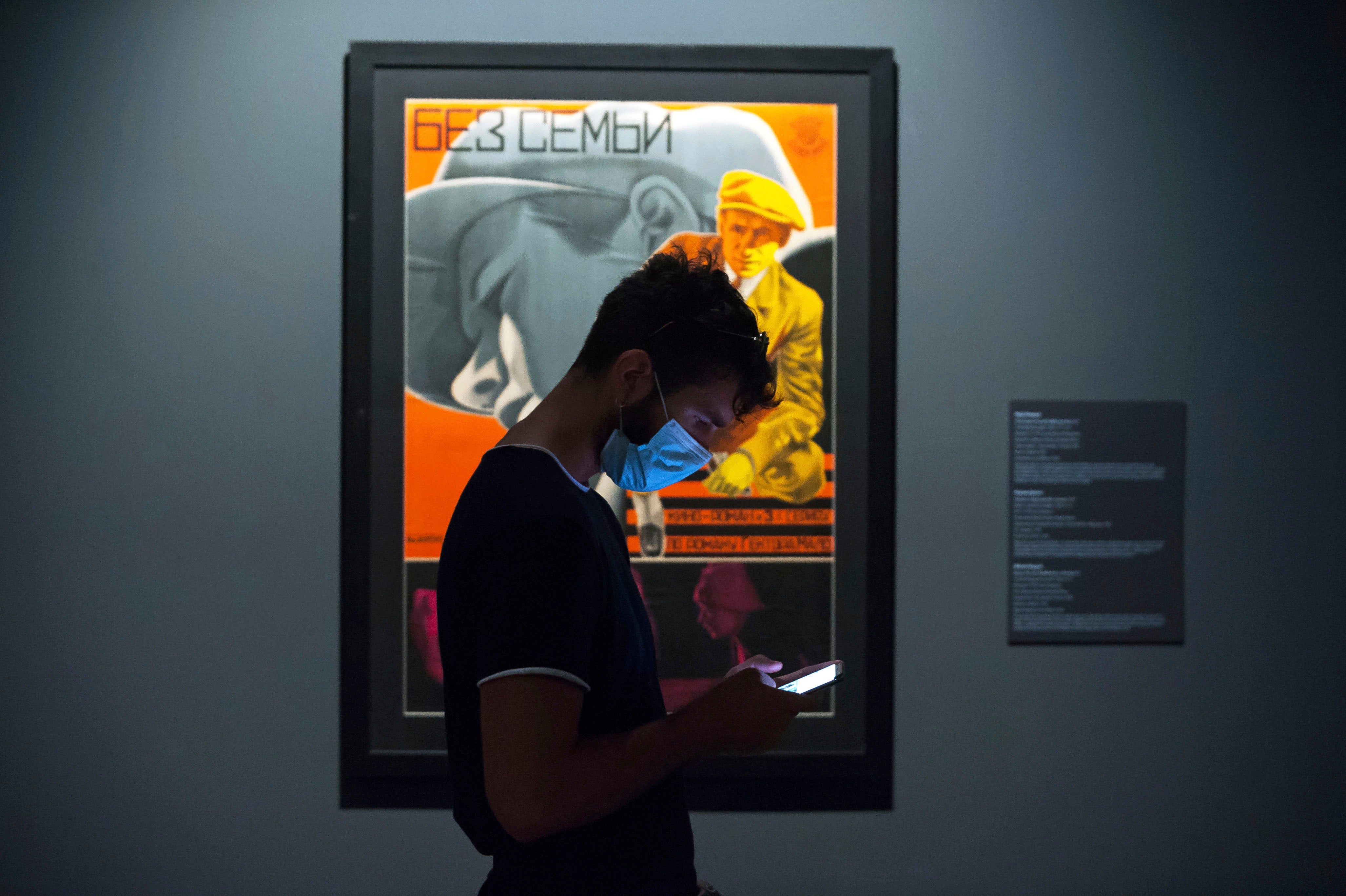 A young man wearing a face mask checks his mobile phone at the State Russian Museum, Saint Petersburg, May 26, 2020.