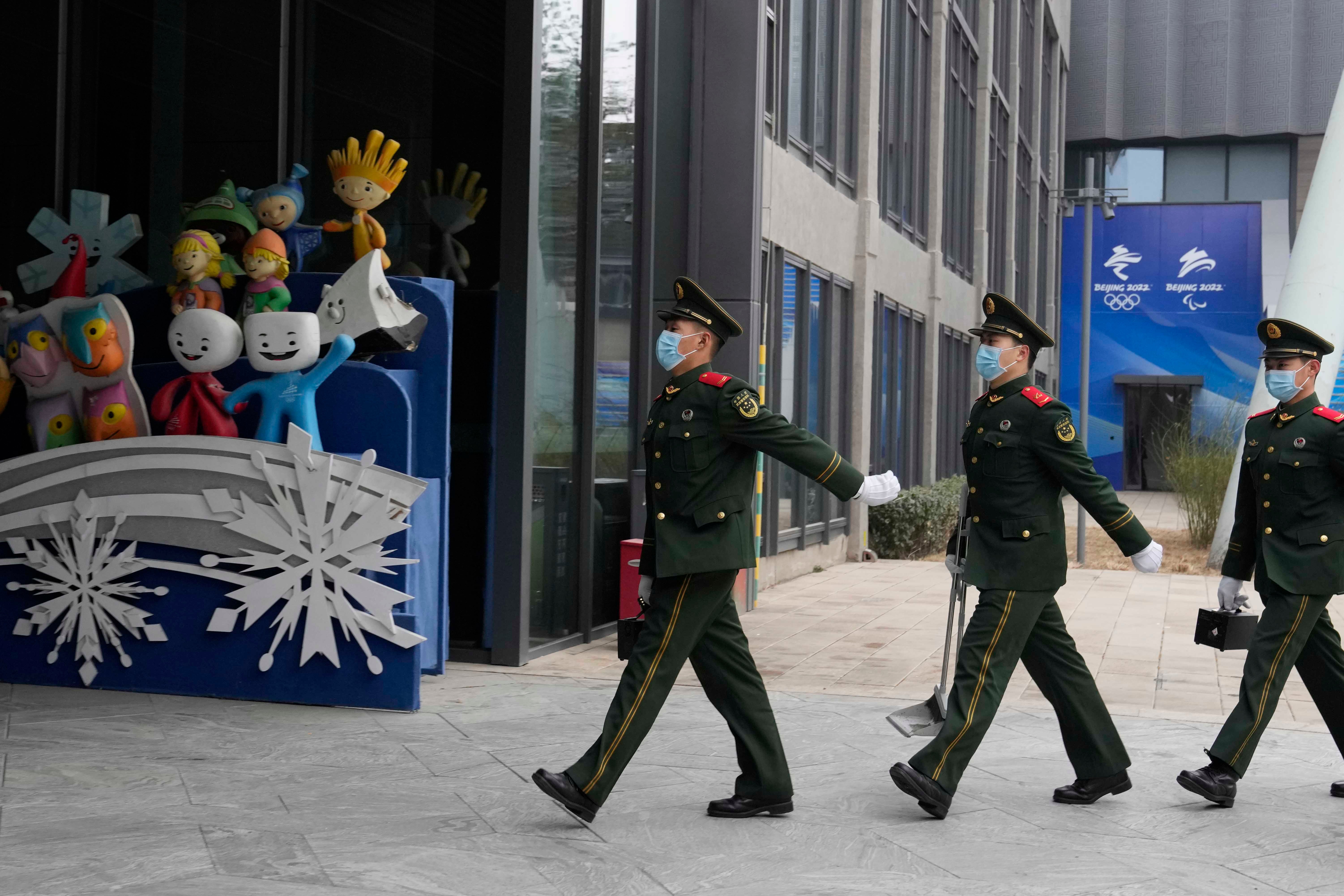 Chinese paramilitary police march past mascots from prior Winter Olympics displayed at Shougang Park in Beijing, China, January 21, 2022. © 2022 AP Photo/Ng Han Guan