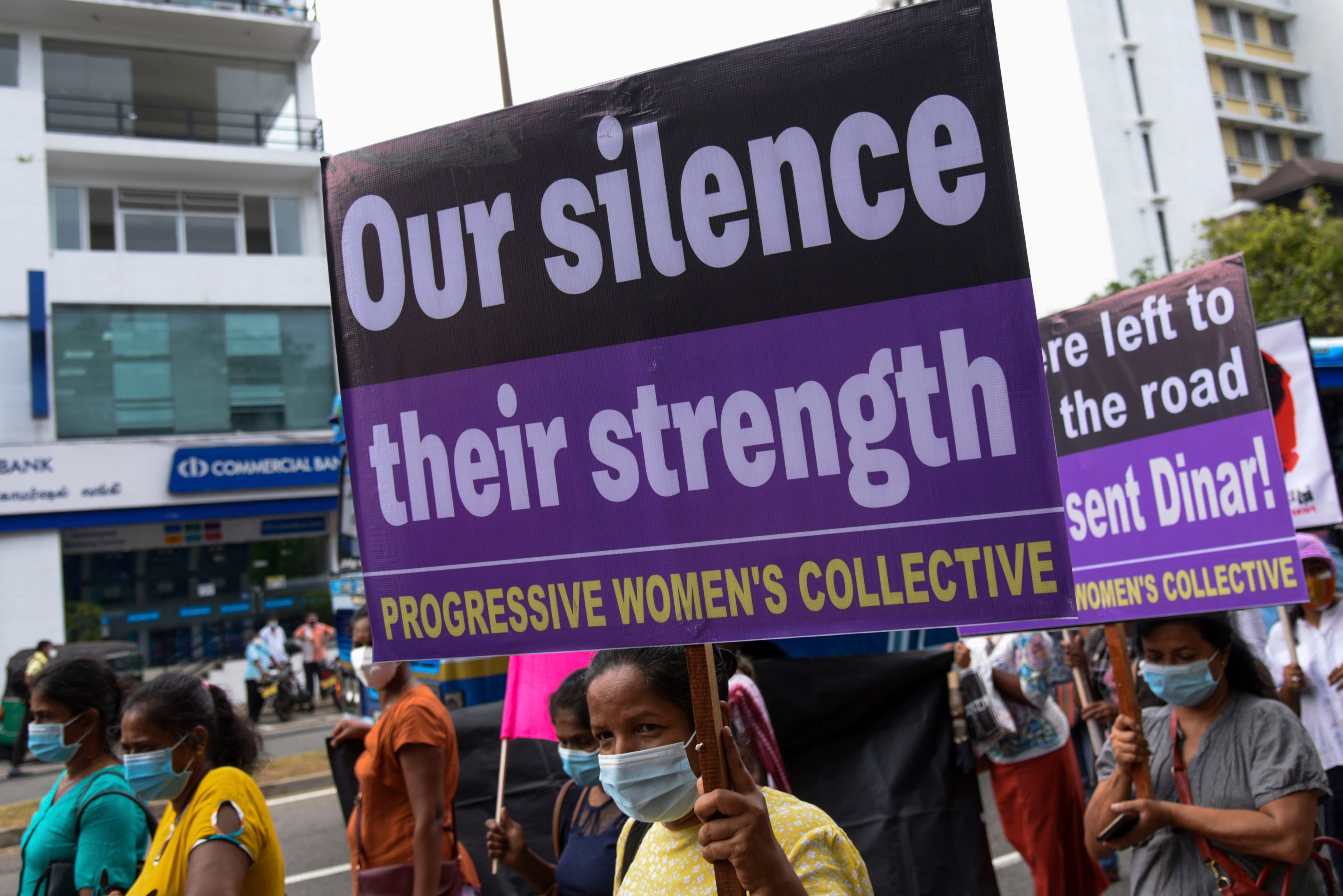 A protester holds a sign that reads "Our Silence, Our Strength"