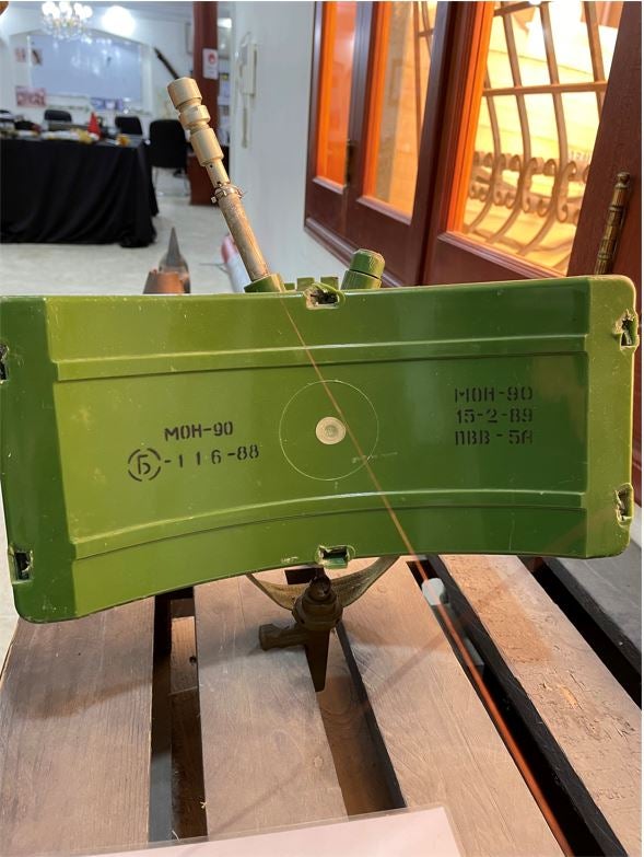 Противопехотная осколочная мина направленного поражения МОН-90 (вид сзади) с взрывателем натяжного действия серии МУВ на экспозиции организации по разминированию Free Fields в Триполи в марте 2022 г. 