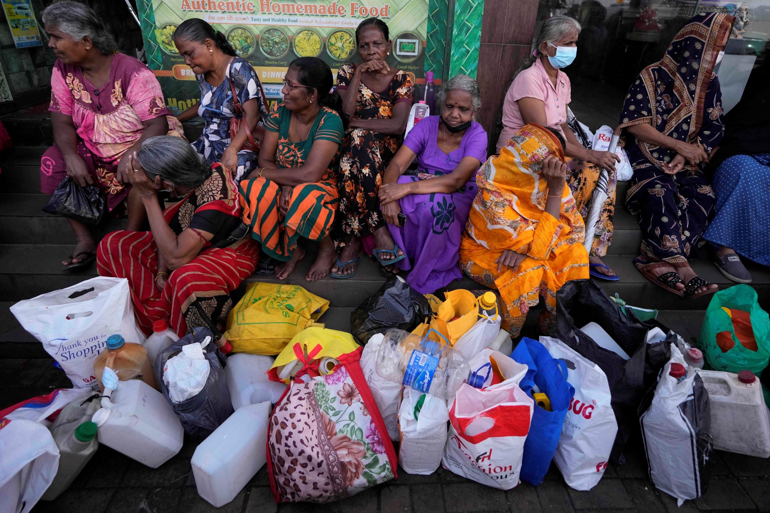Women wait near an empty fuel station