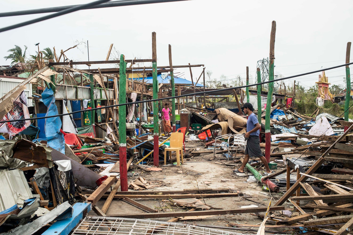  Local residents walk past damaged buildings after Cyclone Mocha in Sittwe township, Rakhine State, Myanmar, May 16, 2023. 