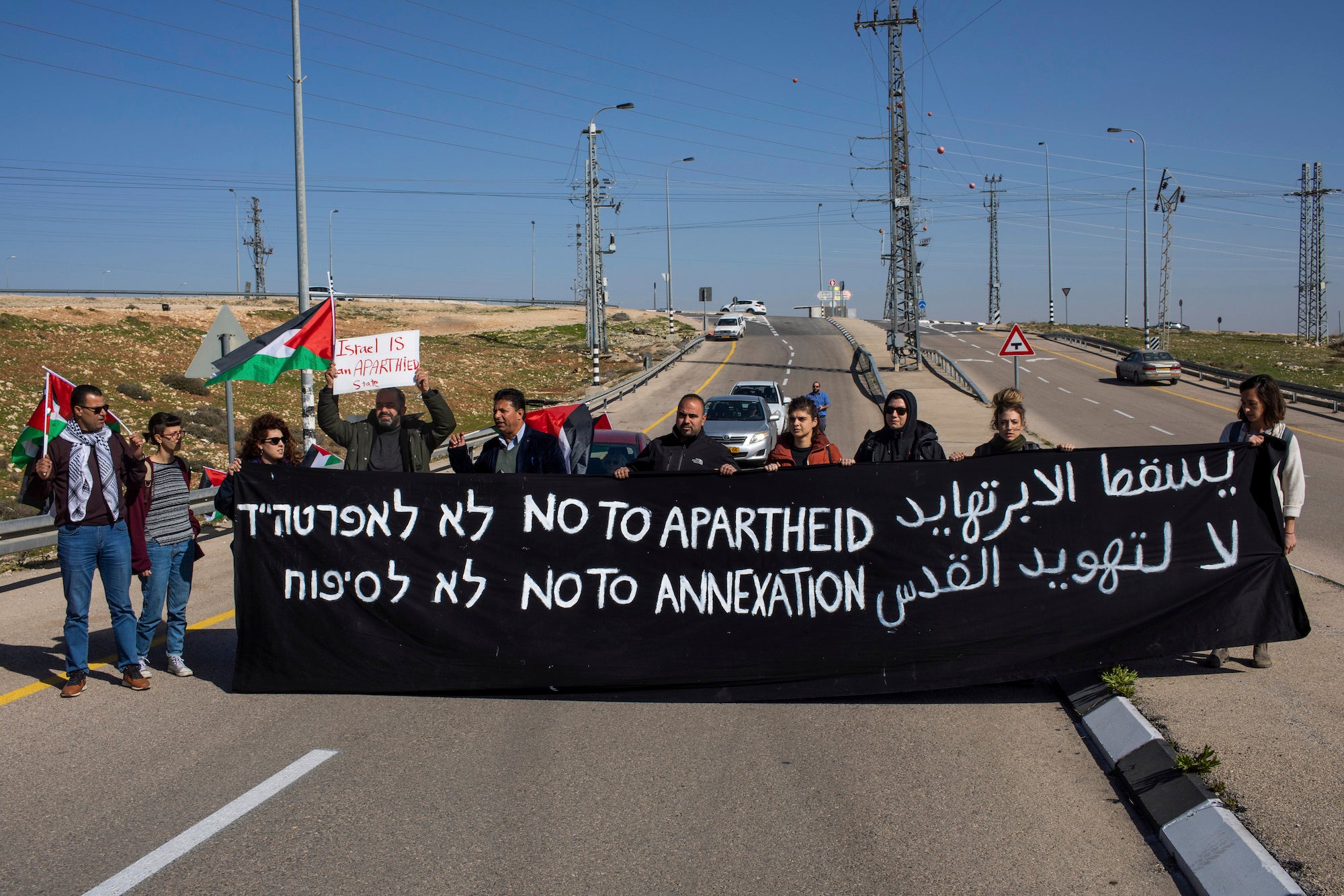  Israeli and Palestine activists hold a banner during a protest to block the new Route 4370 Israeli highway near the Palestinian town of Anata, January 23, 2019.