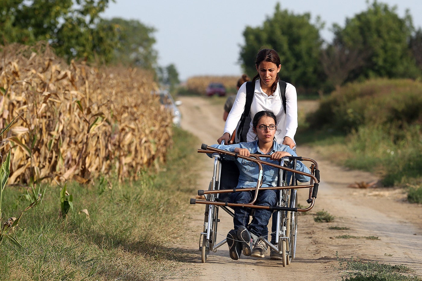 Nujeen, a wheelchair user, and her sister travel down a dirt path after fleeing their native Syria. 
