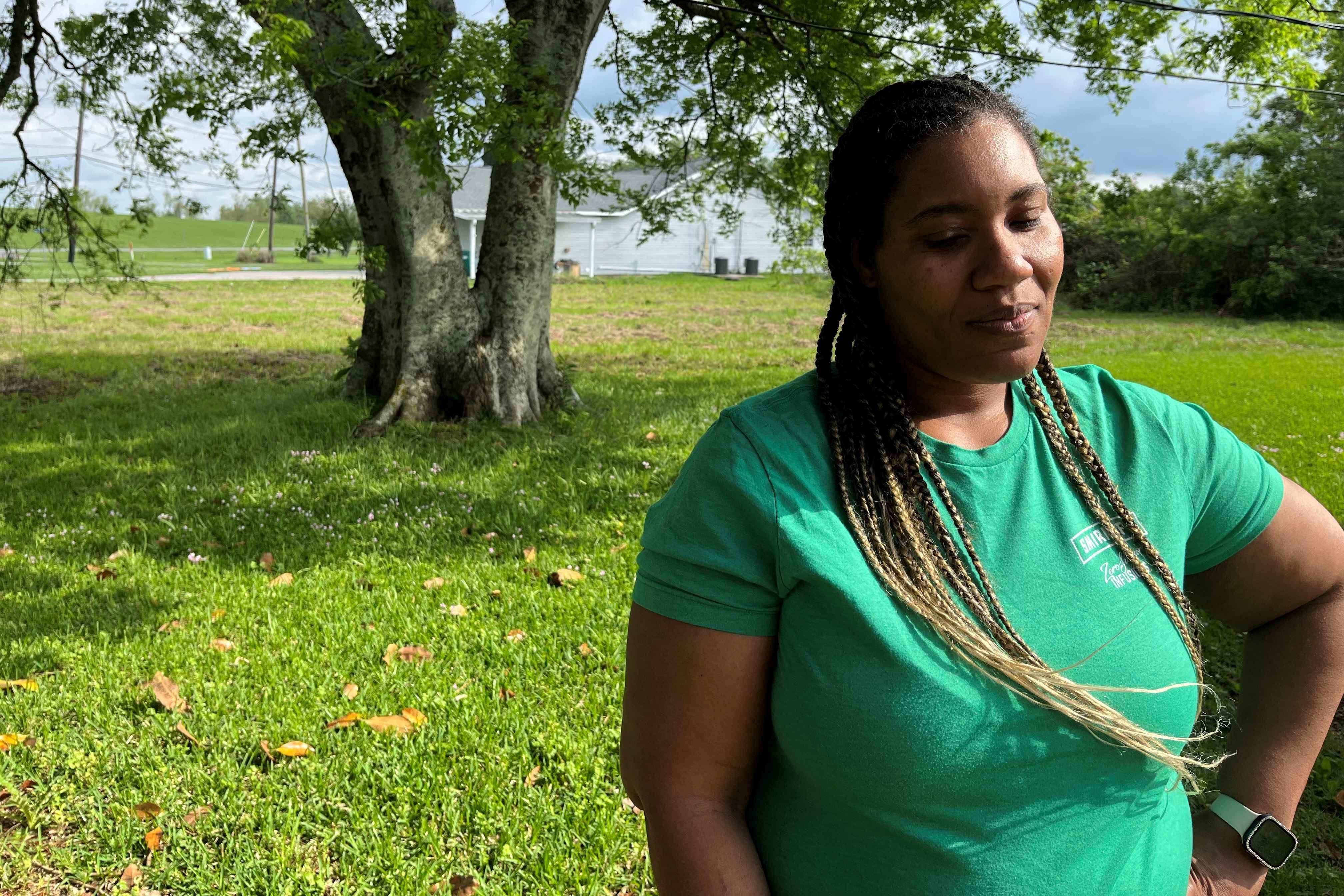 A woman stands outside her home
