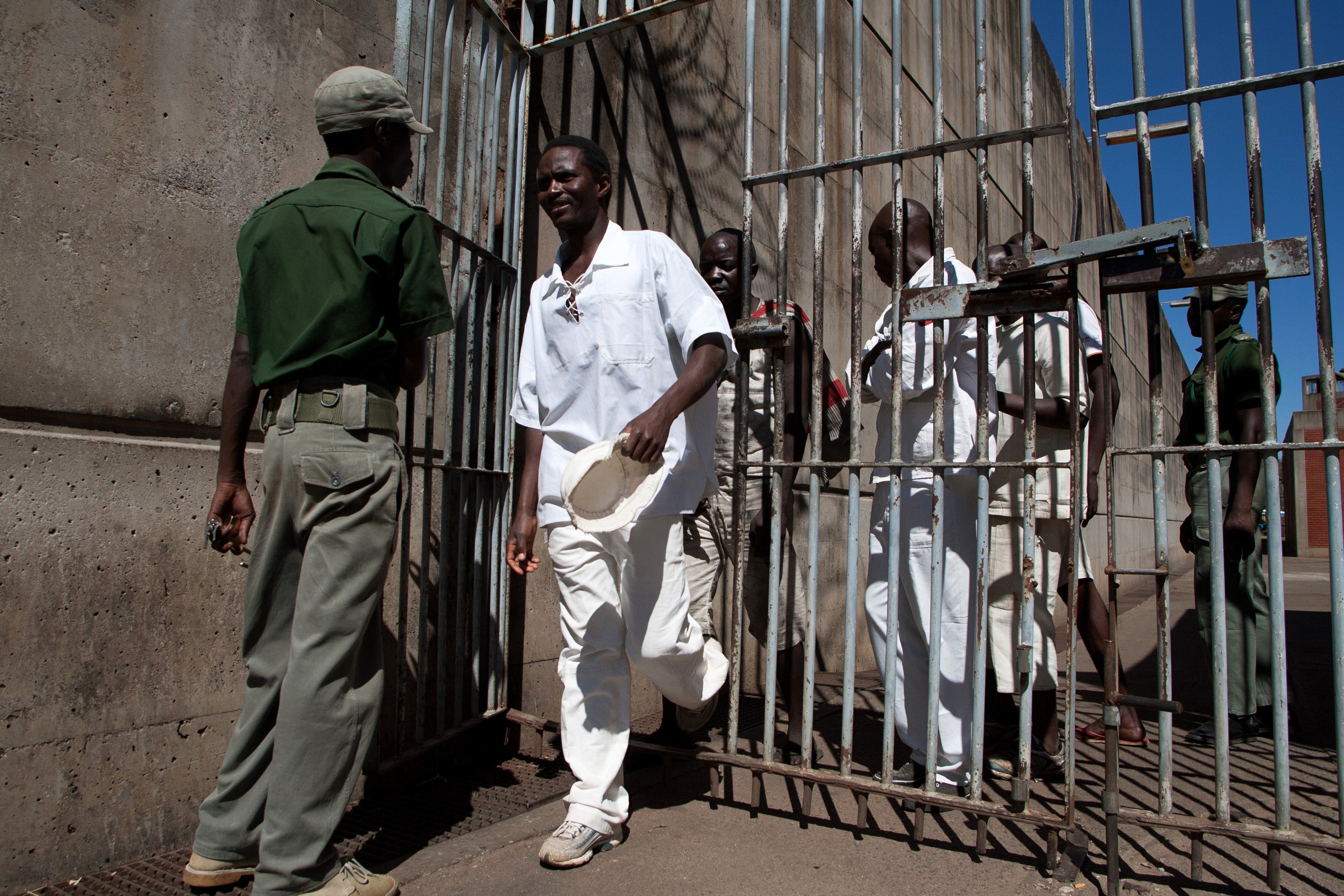 Inmates walk past a prison guard at the Chikurubi maximum security prison in Harare, Zimbabwe, May 20, 2015.