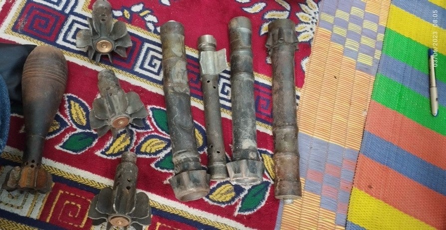 Munitions remnants display next to a pen for scale