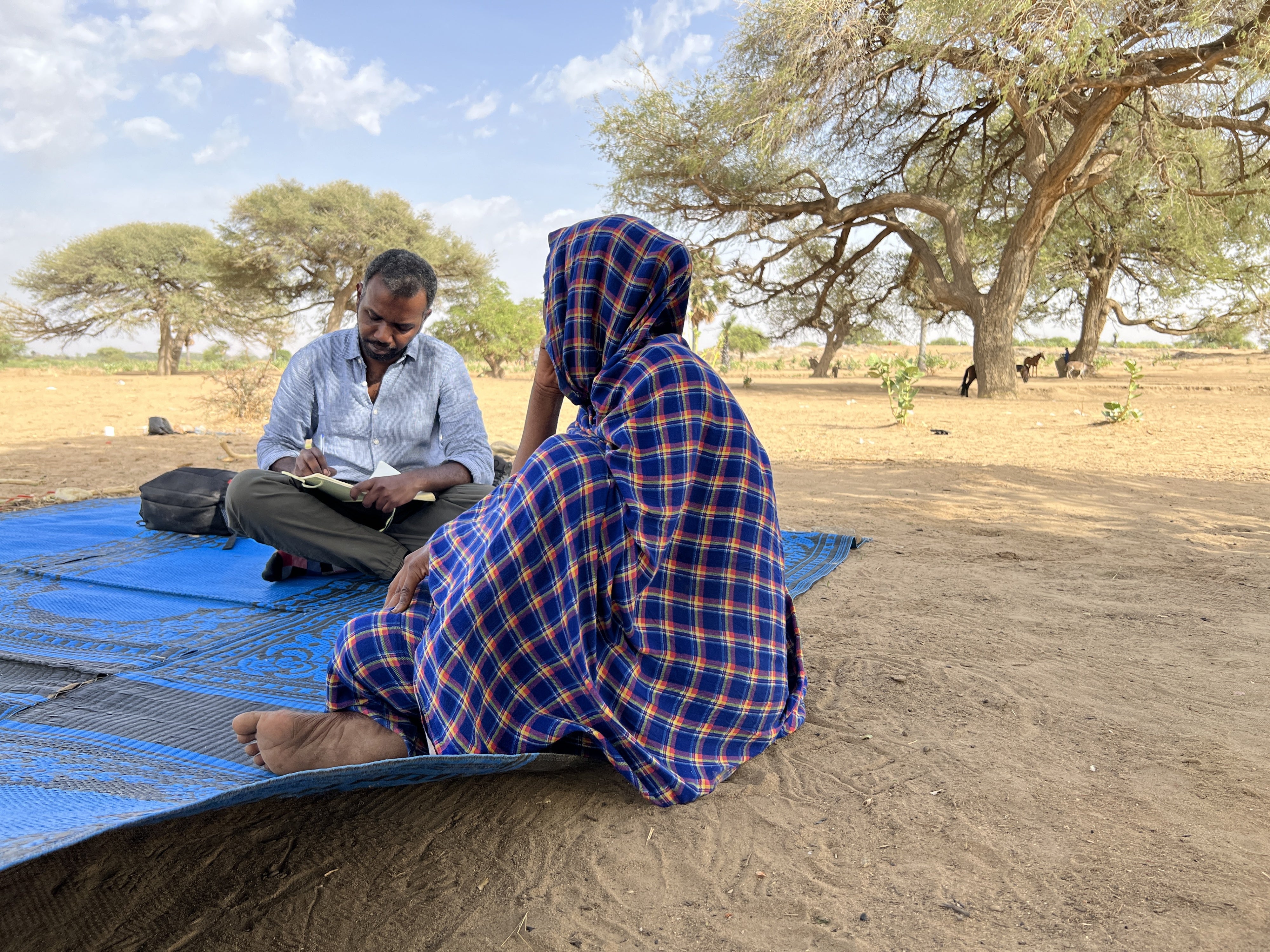 A researcher takes notes while sitting with an interviewee