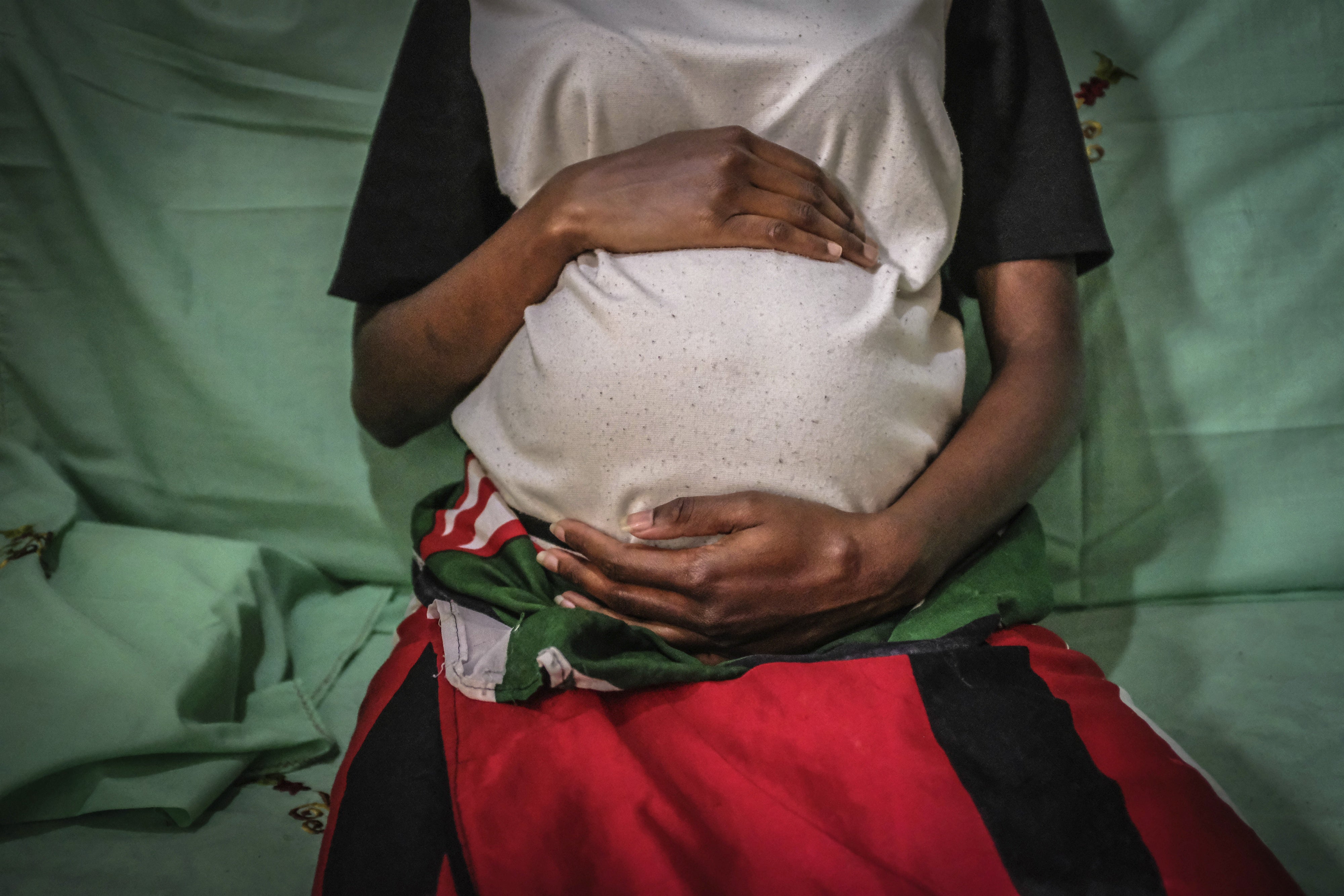 An unidentiable woman poses holding her baby bump