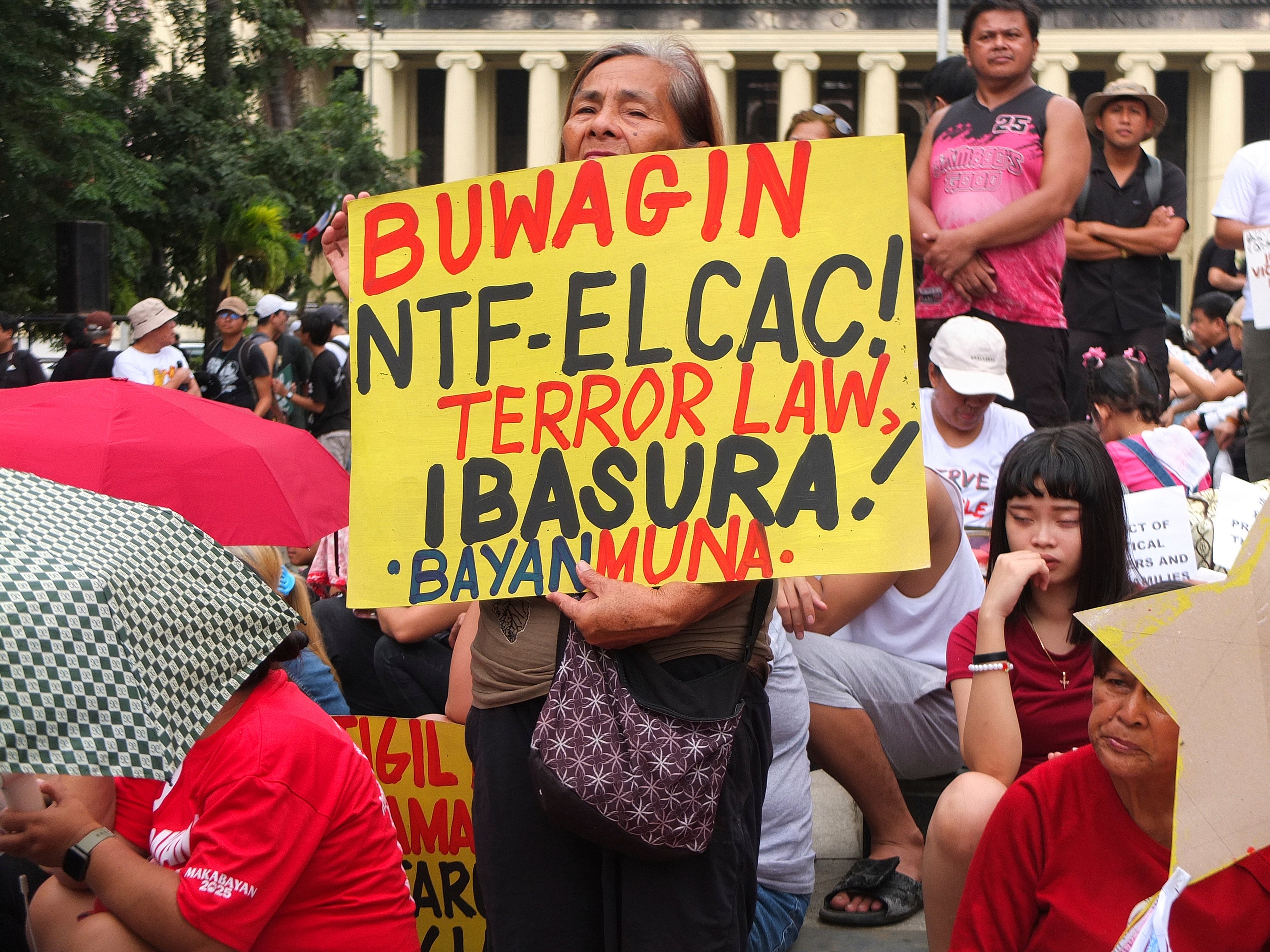 An activist holds a poster calling for abolishing the anti-communist task force