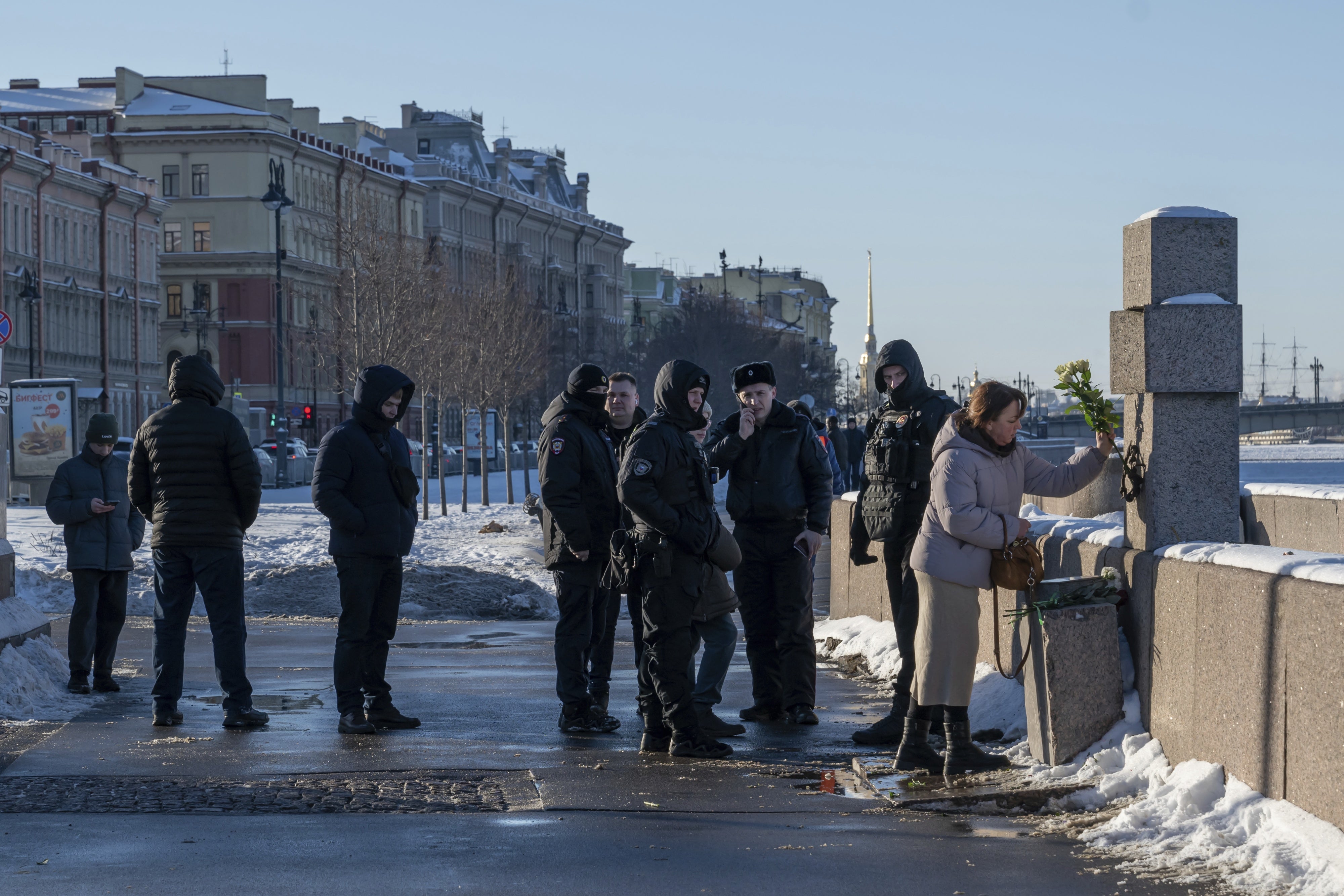 Police watch a woman as she lays flowers at a memorial 