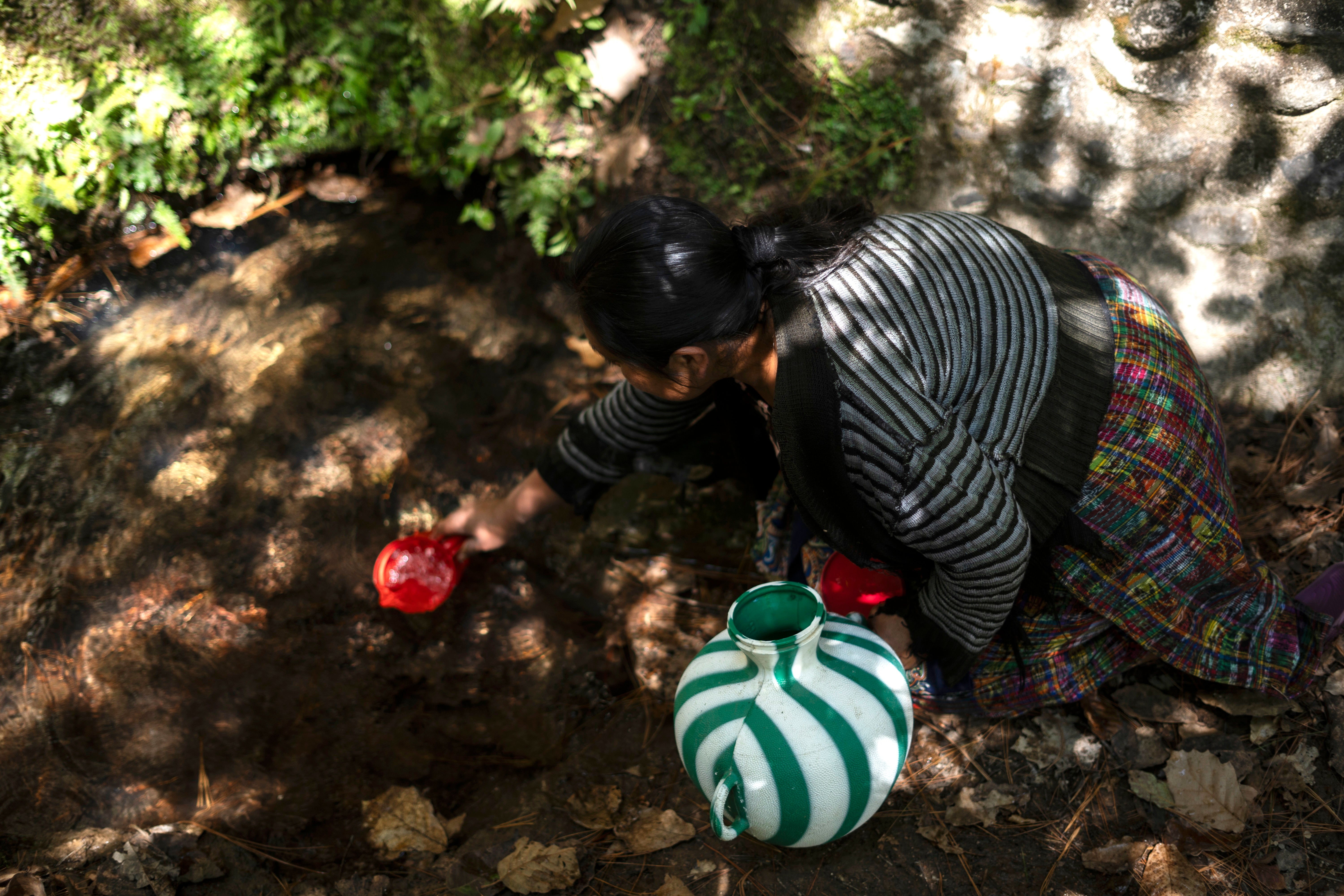 A woman collects water to drink from a well in Santa María Chiquimula municipality, Totonicapán department, Guatemala, March 11, 2025.