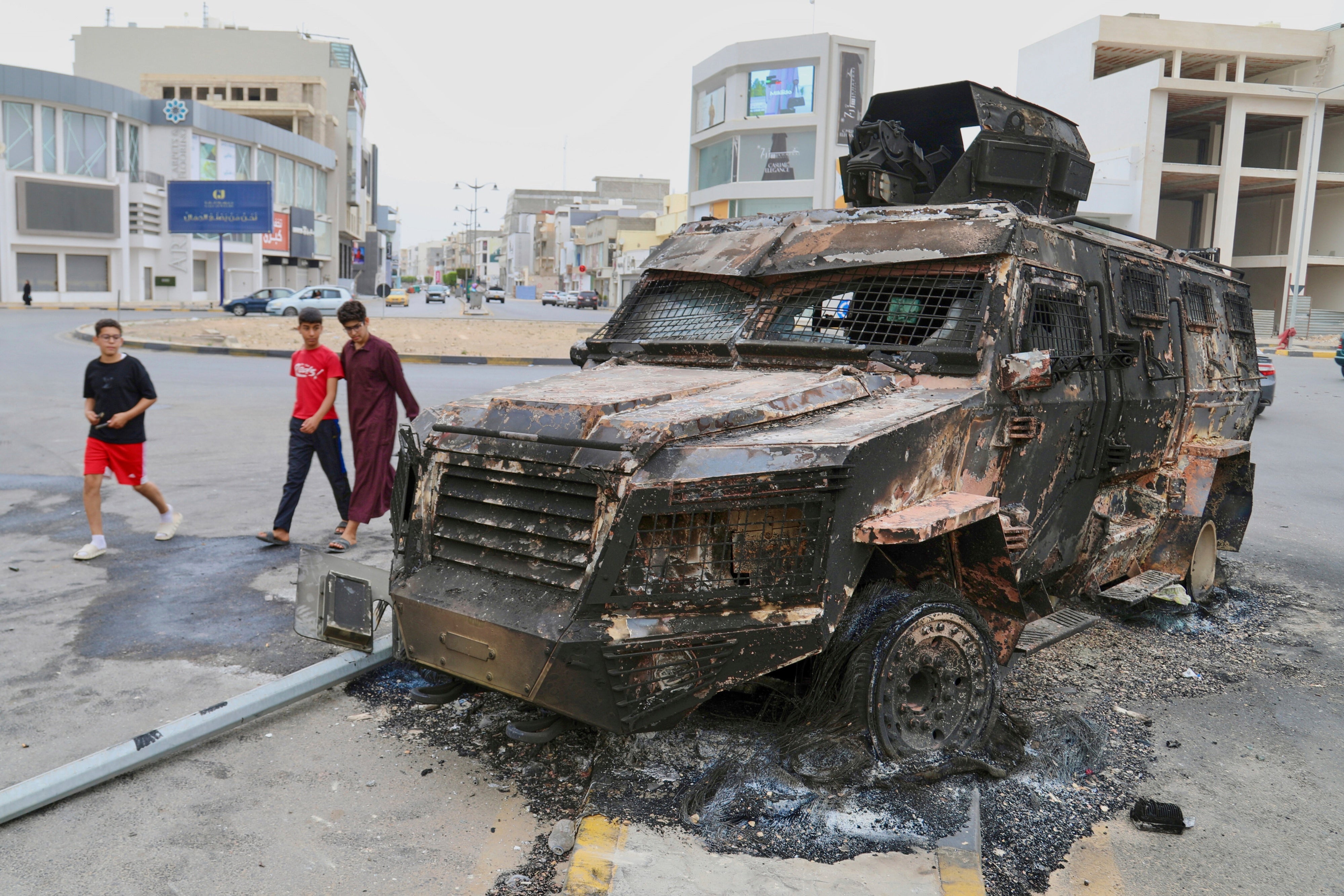 Boys walk past a damaged armored vehicle of an armed group after heavy clashes between militias rocked the capital and resulted in civilian casualties and destruction of homes, Tripoli, Libya, May 14, 2025.