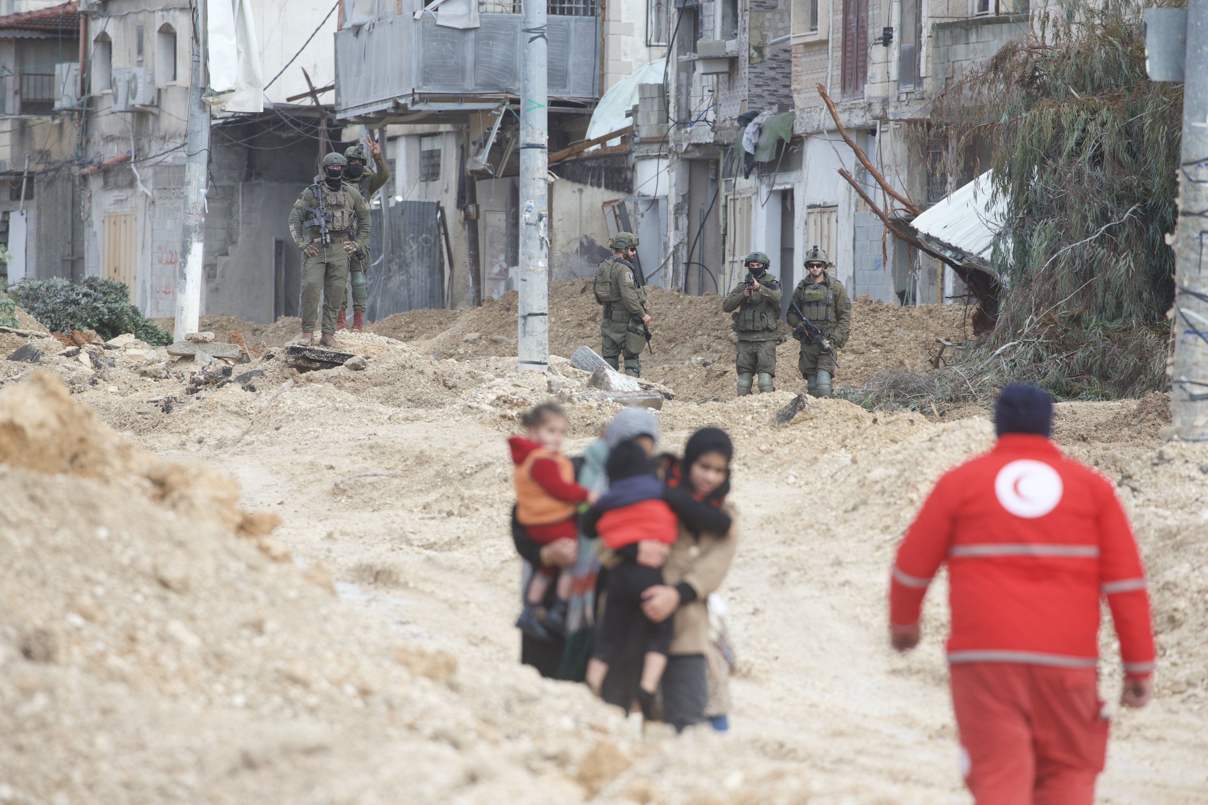 Women carry children as Israeli forces forcibly displace them from Nur Shams refugee camp 