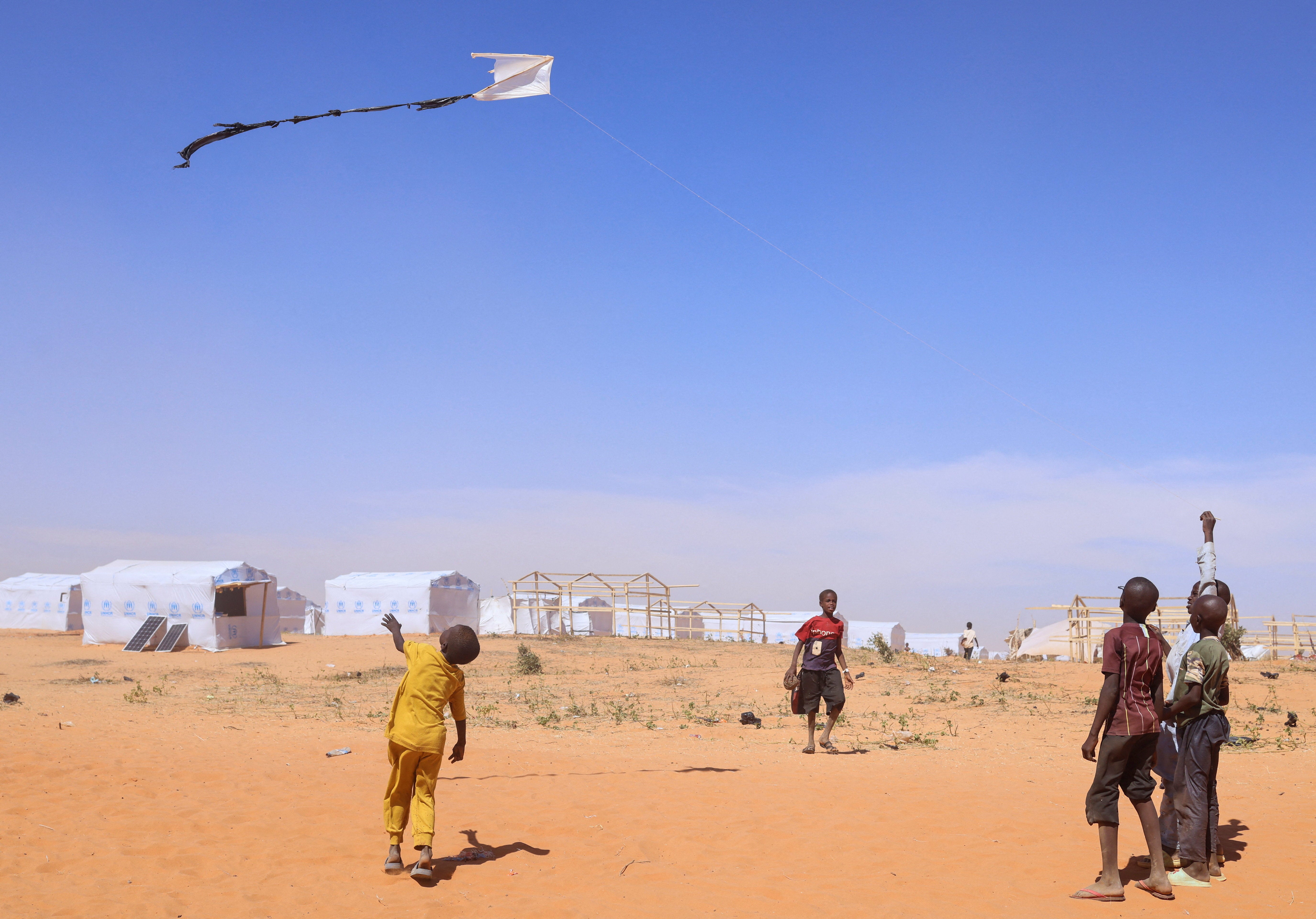 Sudanese refugee children from Darfur fly a handmade kite inside the Touloum refugee camp in Wadi Fira province, eastern Chad, November 30, 2025.