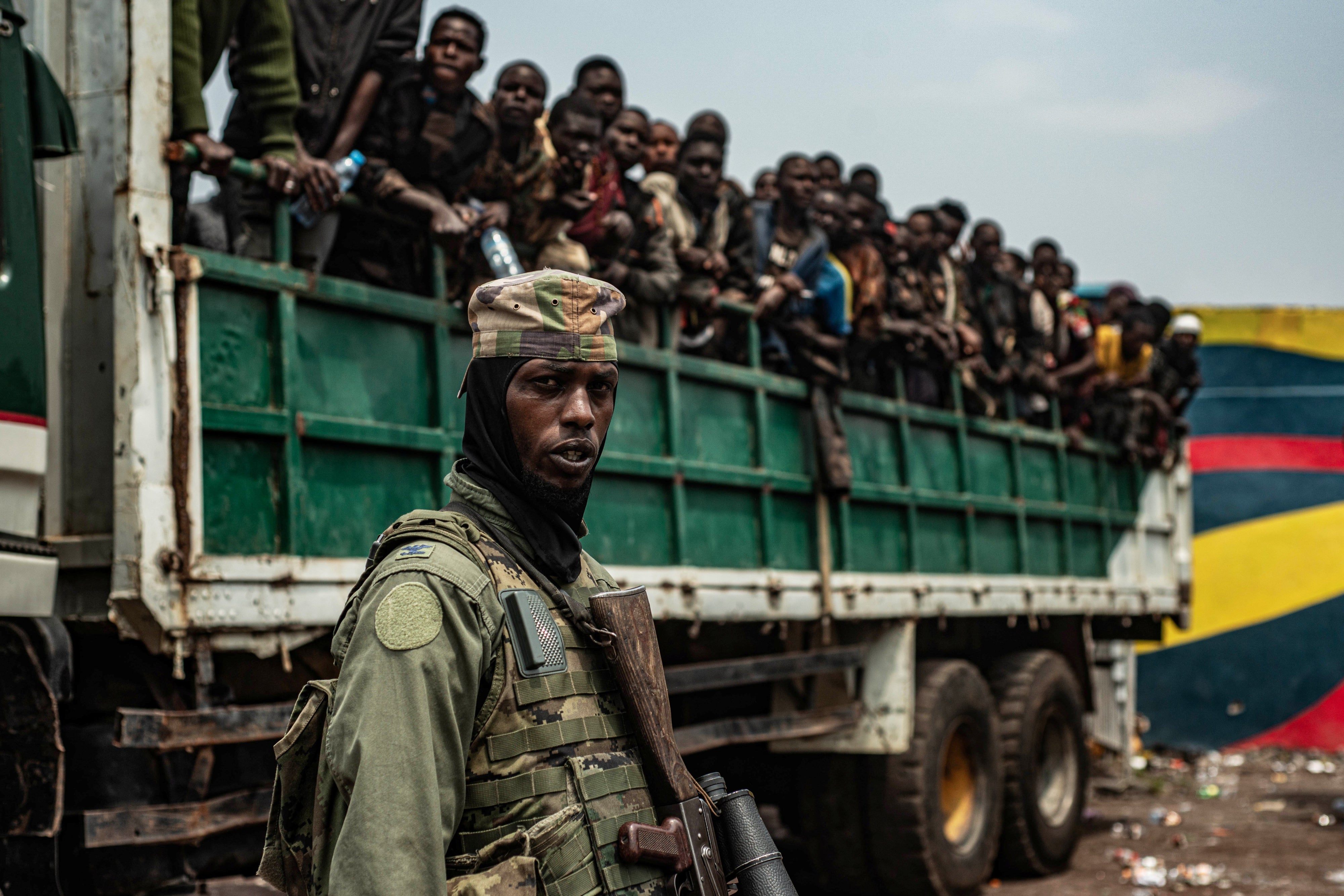An M23 fighter in front of a truck with detained Congolese soldiers.