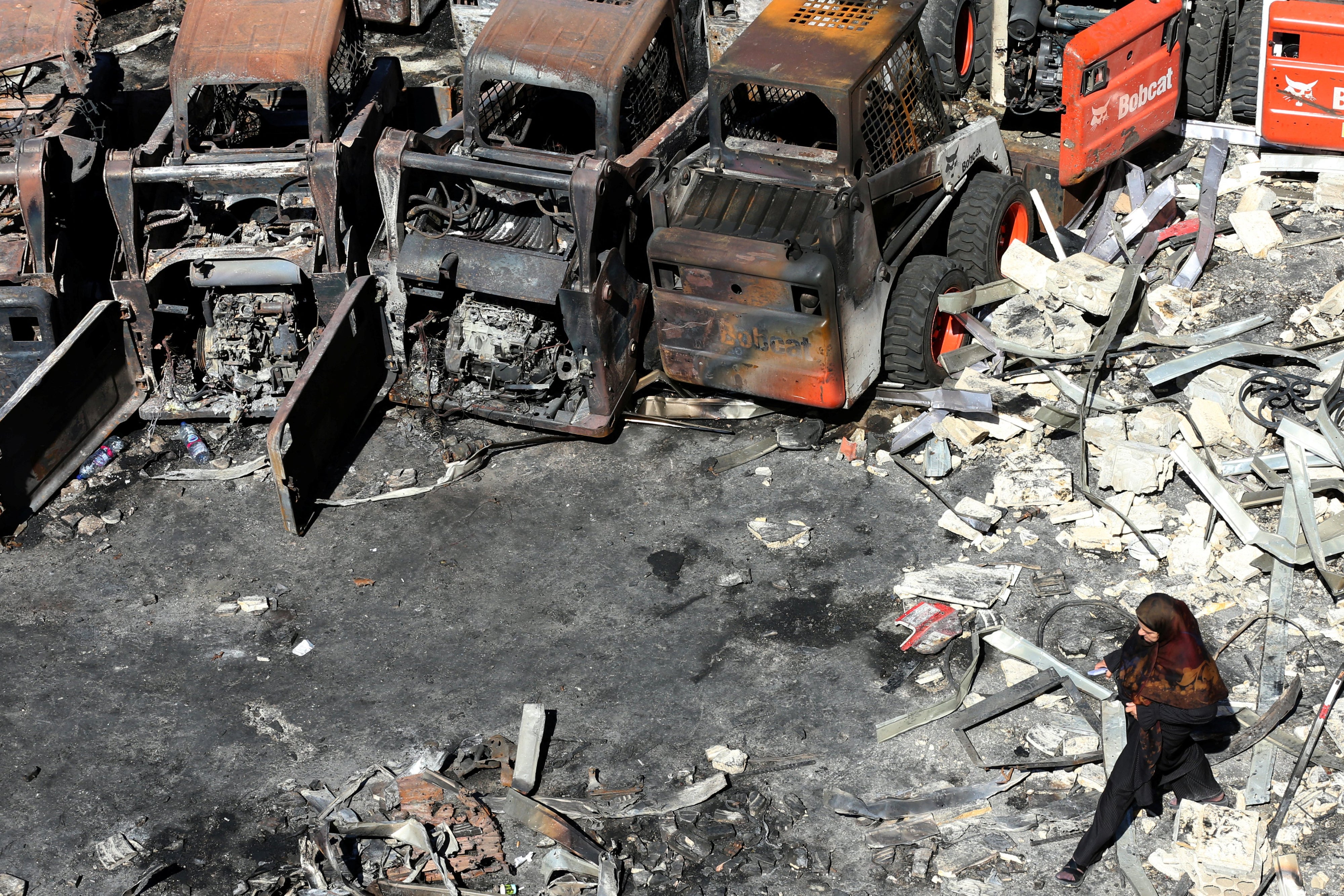 Une femme marchait parmi les décombres près d’équipements agricoles calcinés à la suite d'une frappe israélienne, dans le village de Msayleh situé dans le sud du Liban, le 11 octobre 2025.
