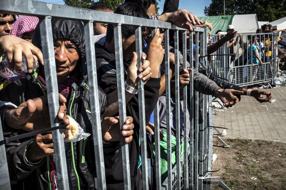 Asylum seekers behind a metal fence in the ‘Hangar 1’ detention center, in Röszke, Hungary.