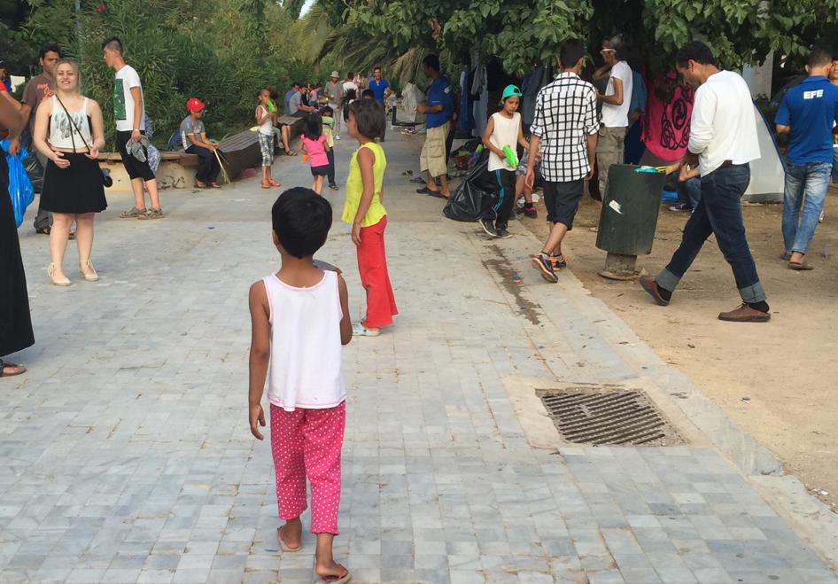 Children from Afghanistan play with a local volunteer at a makeshift camp in Pedion tou Areos. Earlier this week, the government announced a plan to move people from the park to an open camp it plans to create. 