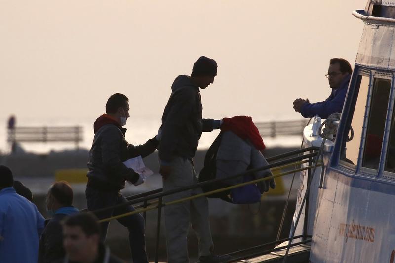 A Frontex officer (L) escorts a deportee onto a boat on the Greek island of Lesbos, April 4, 2016.