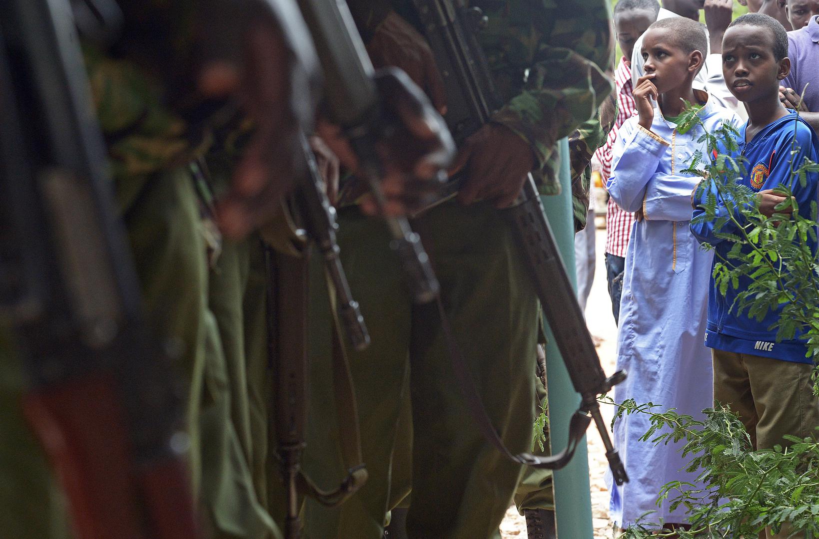 A picture of children looking at Kenyan police carrying guns.