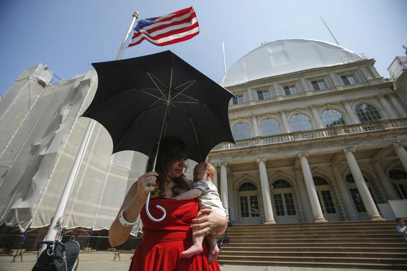 A mother holds her baby while attending a rally to raise public awareness and support for breastfeeding by the steps of New York City Hall in Manhattan, August 8, 2014.