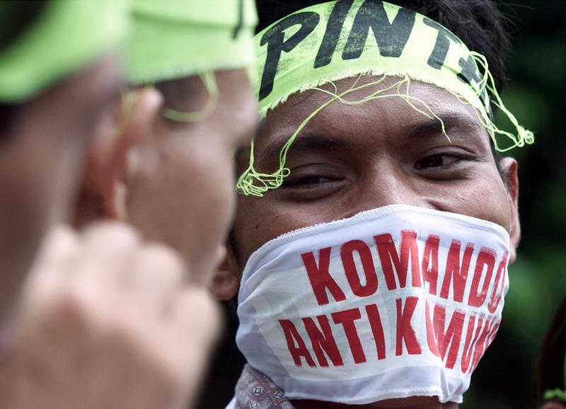 An Indonesian youth covers his face with a mask reading "Anti Communist Command" during a protest in front of the presidential palace in Jakarta May 20, 2000.