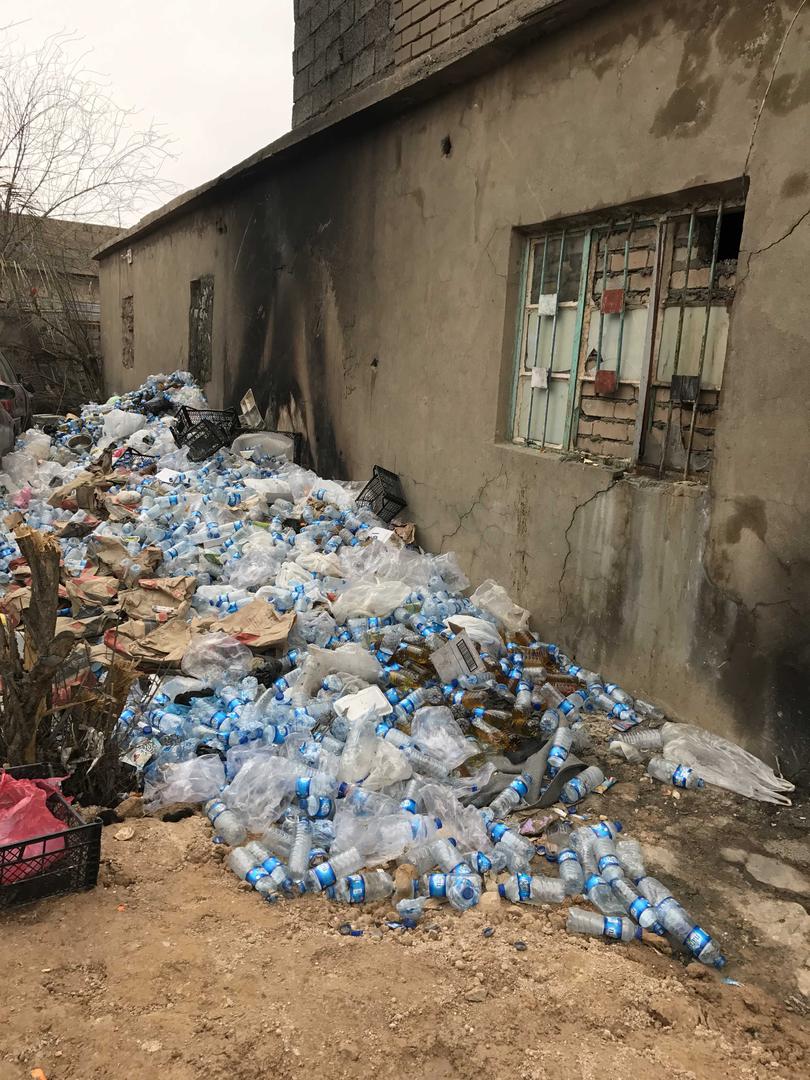 A pile of water bottles filled with urine outside a hole in the wall from a 3 by 4-meter cell holding 38 detainees. 