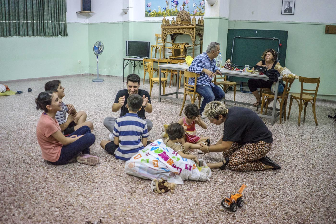 Alexandros plays with Lava, Rudi and Mohammed, while Sperantza helps Elin and Evin to try the new shoes she has given to them. © 2017 Anna Pantelia