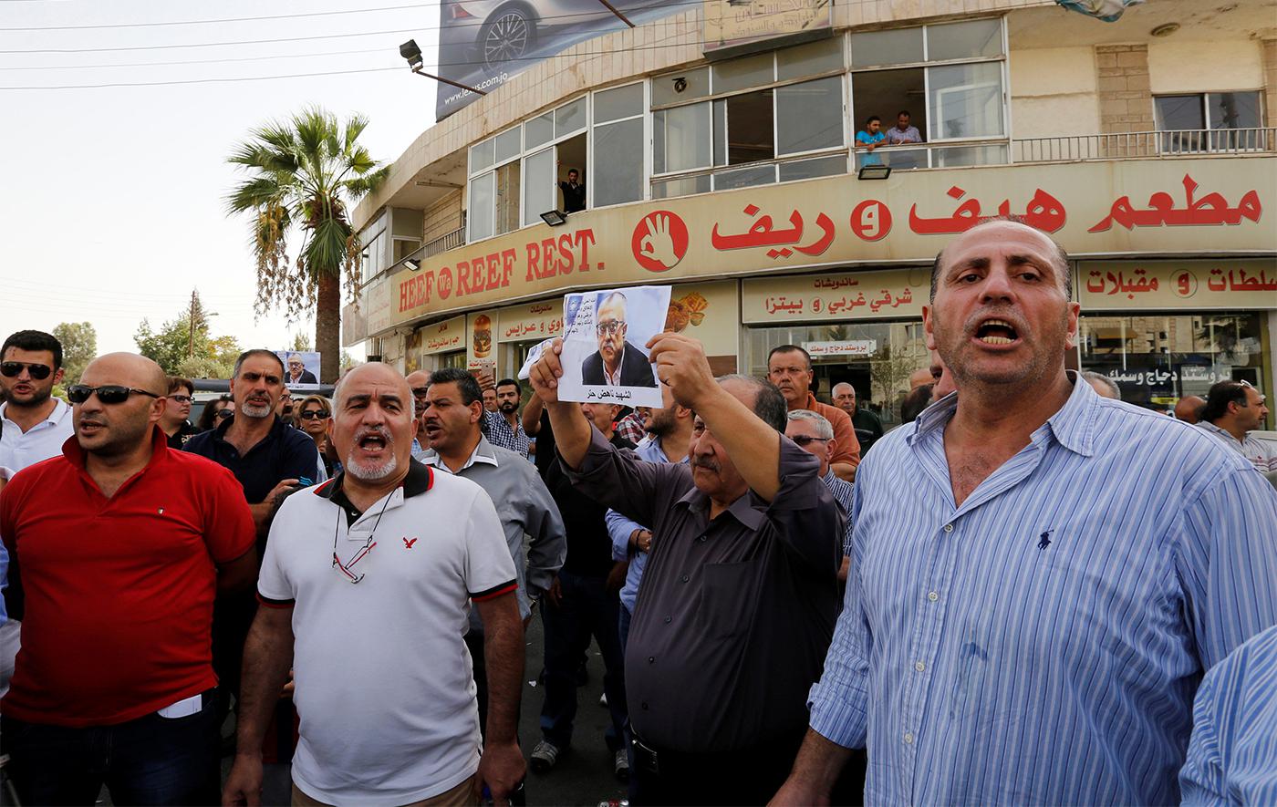 Friends and relatives hold a picture of Jordanian writer Nahed Hattar, who was shot dead, during a sit-in in front of the prime minister's building in Amman, Jordan on September 25, 2016.