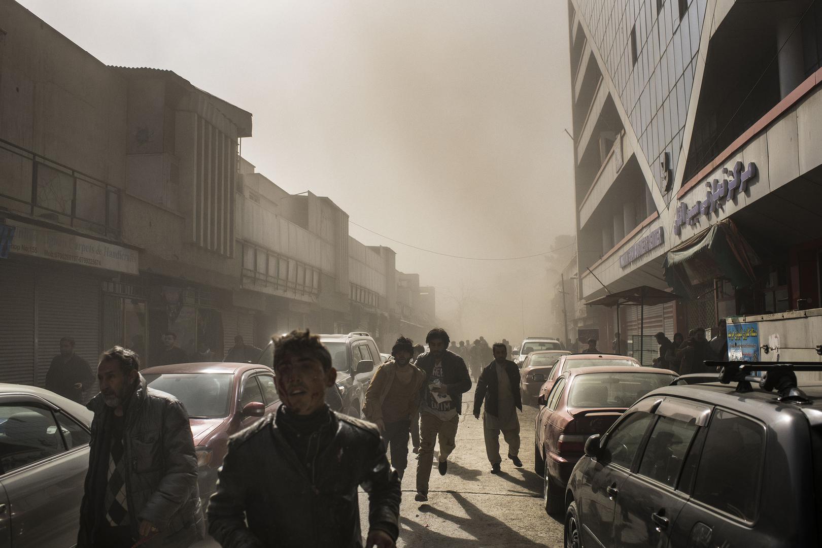 People flee after an ambulance rigged with explosives detonated in central Kabul, killing 103, January 27, 2018.