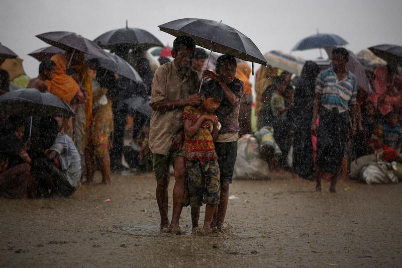 Rohingya refugees try to take shelter from torrential rain as they are held by the Border Guard Bangladesh (BGB) after illegally crossing the border, in Teknaf, Bangladesh, August 31, 2017.