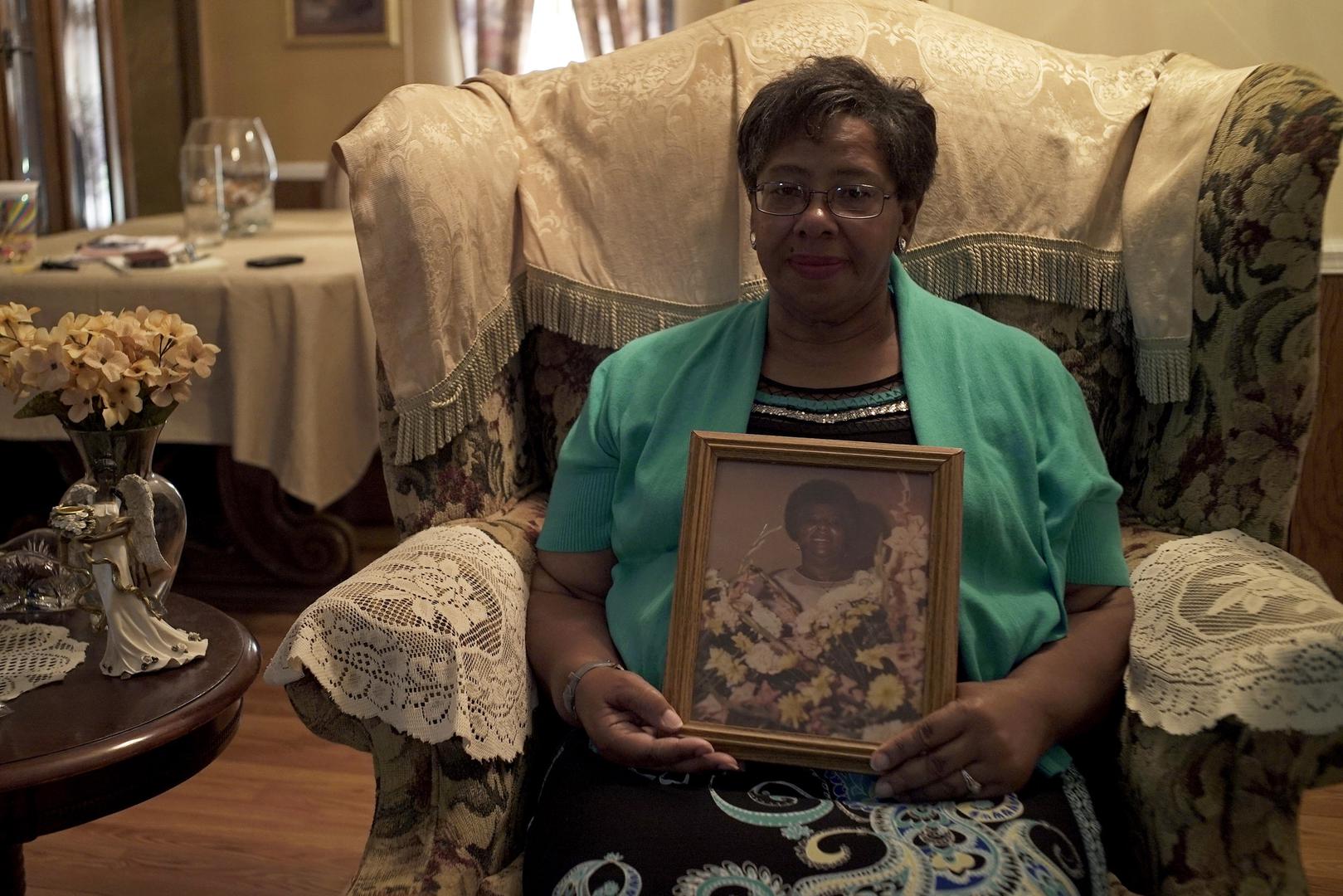 Ms. Frances Ford, executive director of Sowing Seeds of Hope, in her home in August 2018, holding a picture of her mother, who died from cervical cancer after being diagnosed in 1980. 