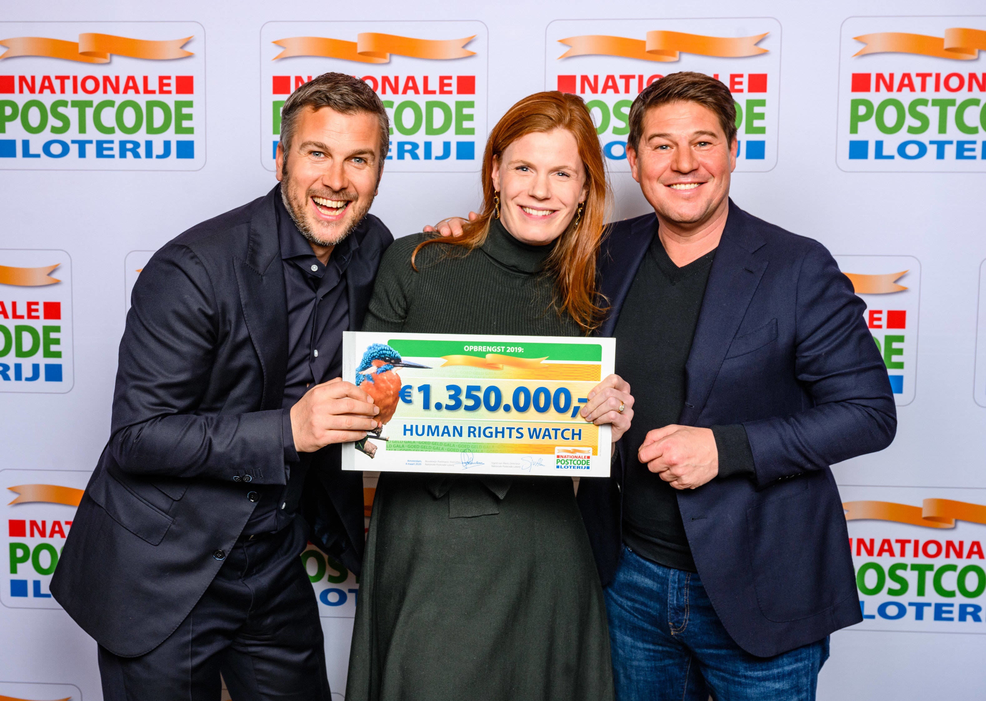 Two men and a woman holding a sign and smiling