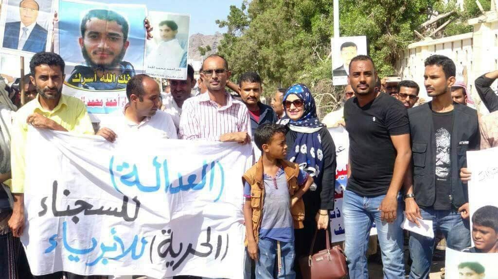 Demonstrators hold up pictures of detainees and a sign demanding "Justice for the prisoners and justice for the innocent" during a 2017 demonstration in Aden, Yemen. 