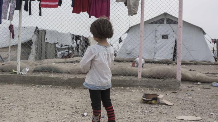 A girl stands in front of a chainlink fence