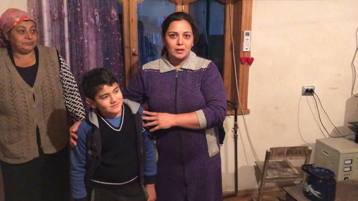 Image of a woman holding her young son as she is interviewed