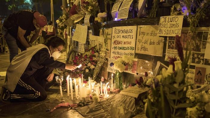 Una mujer enciende una vela en el monumento para los manifestantes que fueron heridos o fallecieron en Lima en noviembre de 2020, afuera del edificio del Congreso de Perú.