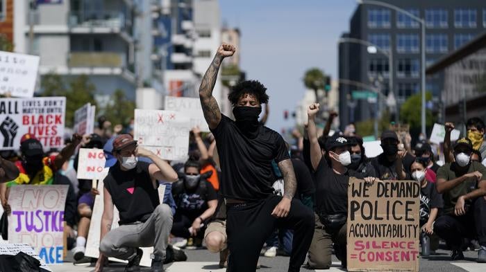 Demonstrators kneel outside the Long Beach Police Department in Long Beach, California during a protest on May 31, 2020. 
