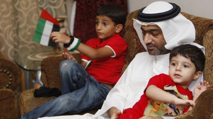 A man sits on a couch with two boys
