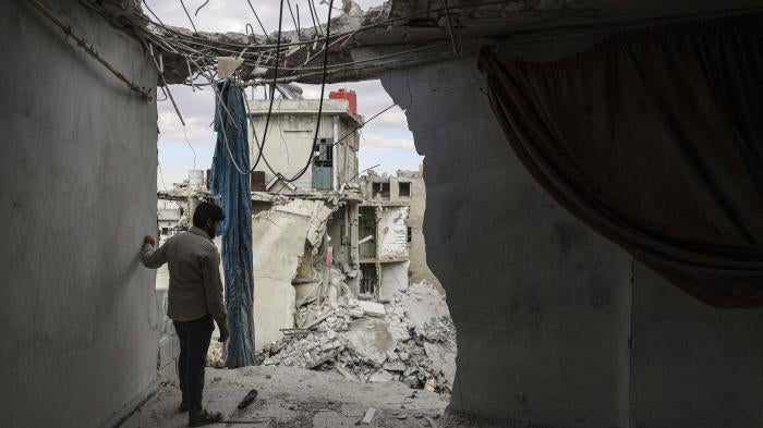 A man stands amongst rubble in an apartment building