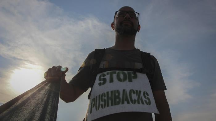 A man holds a banner during a protest against the violent pushbacks of migrants, allegedly conducted by Croatian police, near the border crossing between Croatia and Bosnia and Herzegovina