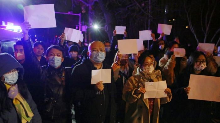 Protesters hold up blank sheets of white paper